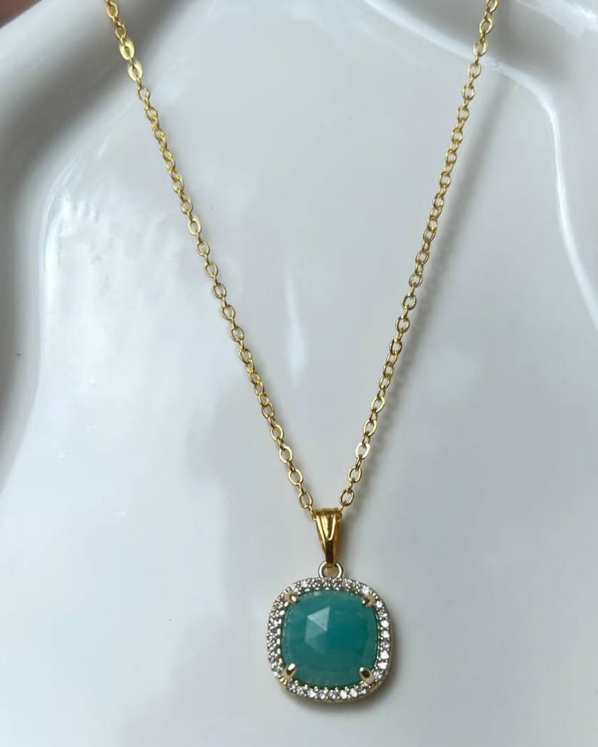 Gold necklace with a turquoise pendant on a white dish
